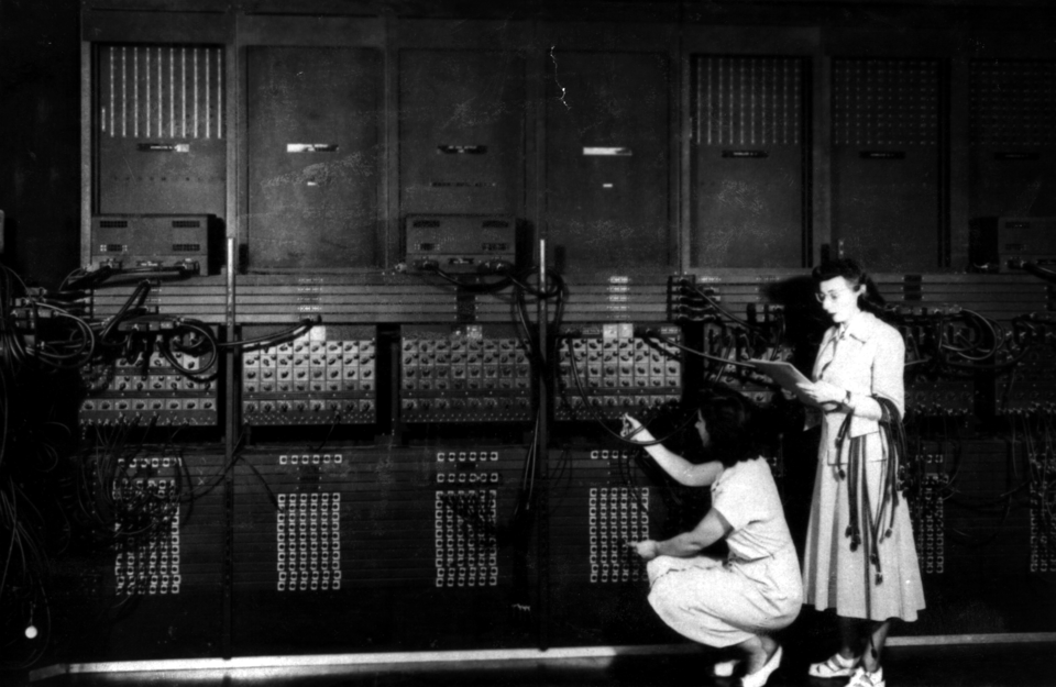 Women programming the ENIAC (Wikimedia Commons). Two women programming the ENIAC computer by plugging in cables.